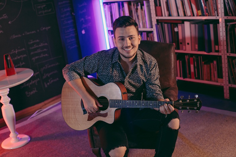 Pedro Thomé tocando violão sentado