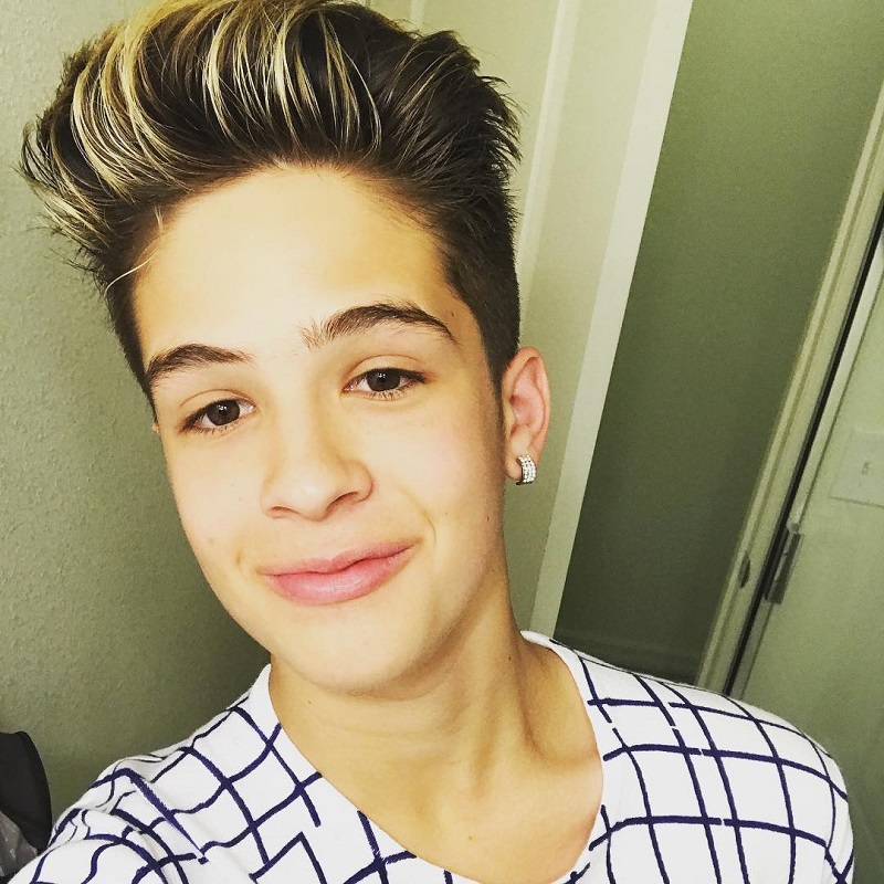 João Guilherme sorrindo, usando camiseta quadriculada