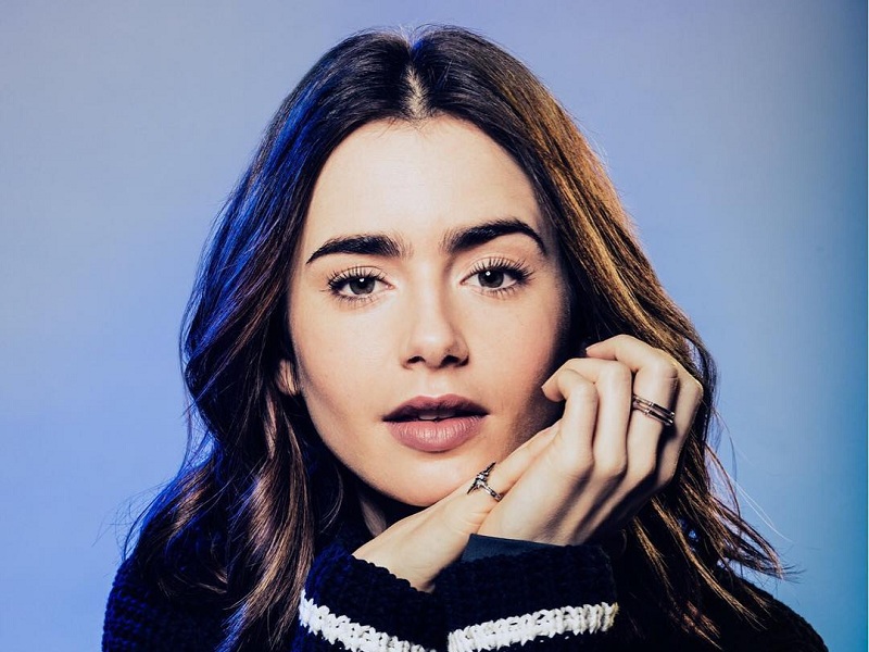 Lily Collins de mãos dadas olhando para frente