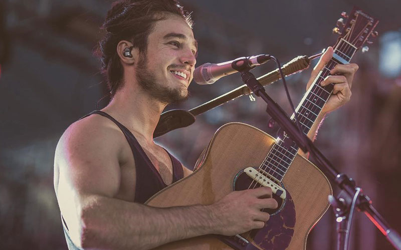 Tiago Iorc sorrindo e tocando violão