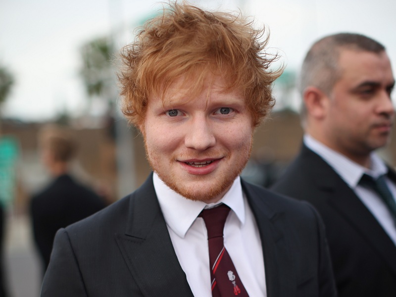 Ed Sheraan sorrindo de terno