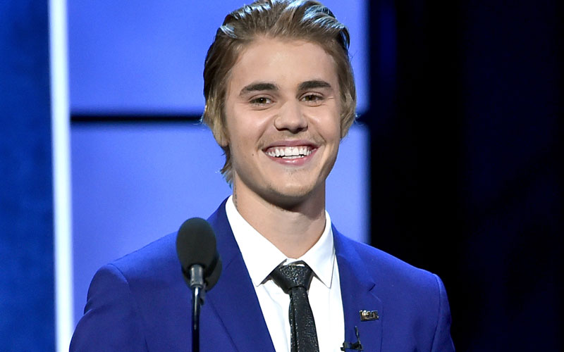 Justin Bieber sorrindo e usando um terno azul