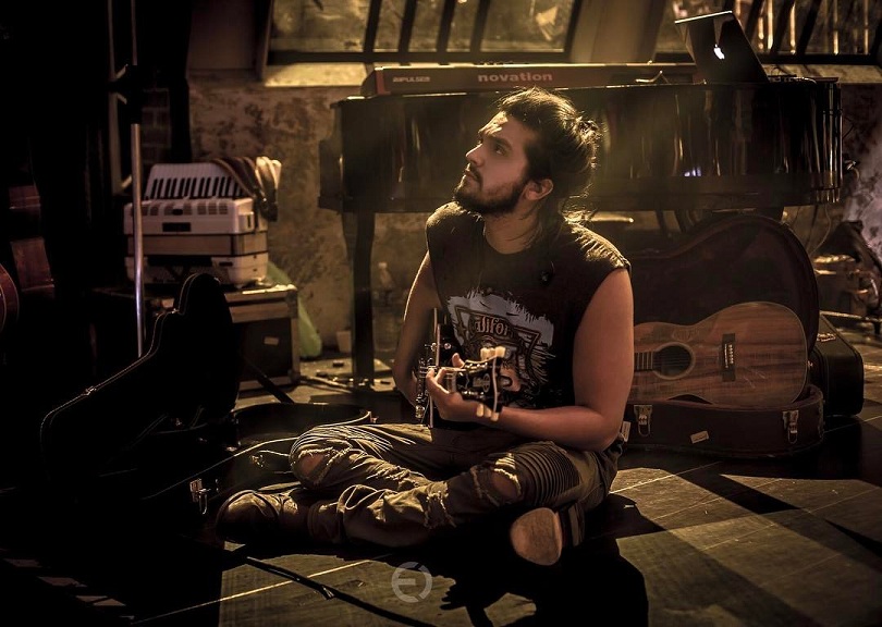 Luan Santana sentado no chão tocando violão