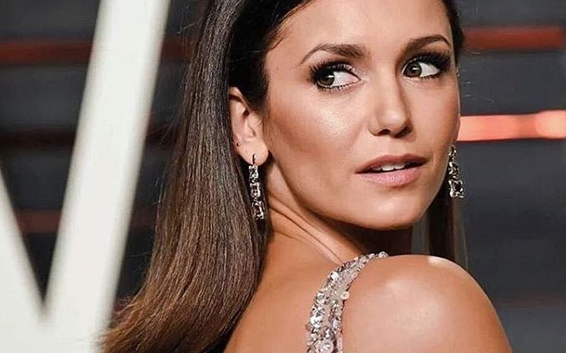 Nina Dobrev de costas com um vestido de pedrarias