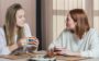 Duas mulheres conversando e tomando café na mesa