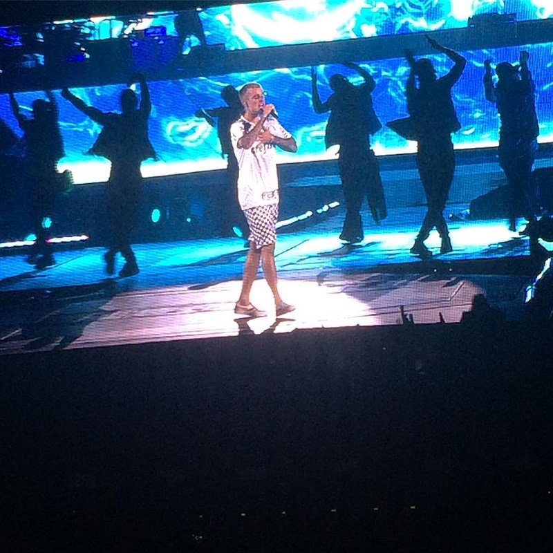 Justin no palco de camiseta o palmeiras e bermuda cantando Sorry