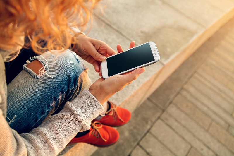Menina ruiva com celular na mão