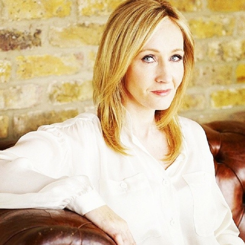 J. K. Rowling olha para a câmera, sentada, usando camisa branca