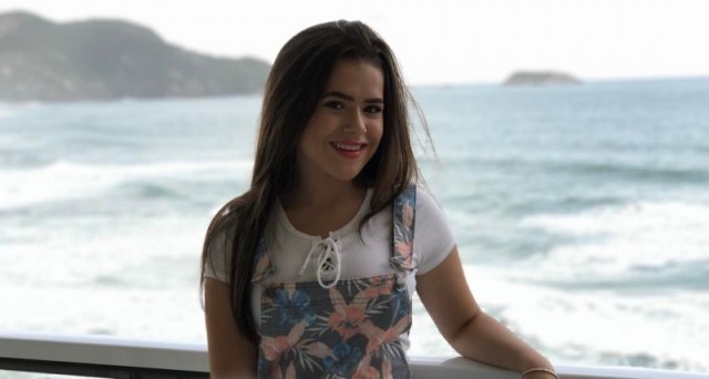 maisa posa em frente ao mar usando camiseta branca e macacão estampado