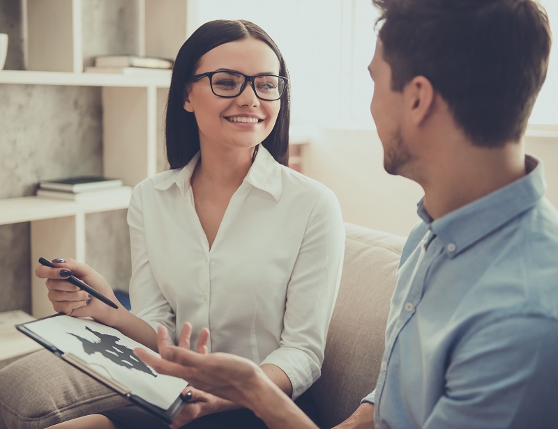 Homem se consultando com uma psicóloga sorridente