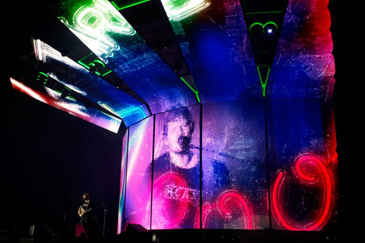 Show do Ed Sheeran. O cantor está no palco, enquanto sua imagem está no telão atrás.