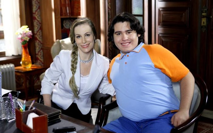 filipe usando figurino de uniforme escolar, gordinho e sem barba, ao lado de atriz de chiquititas