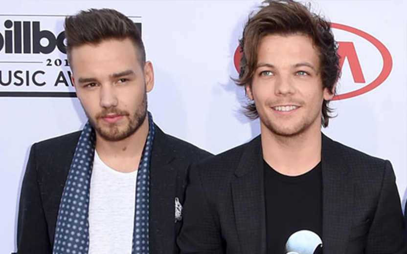 Liam Payne e Louis Tomlinson com roupas pretas e brancas, sorrindo, durante tapete vermelho de evento