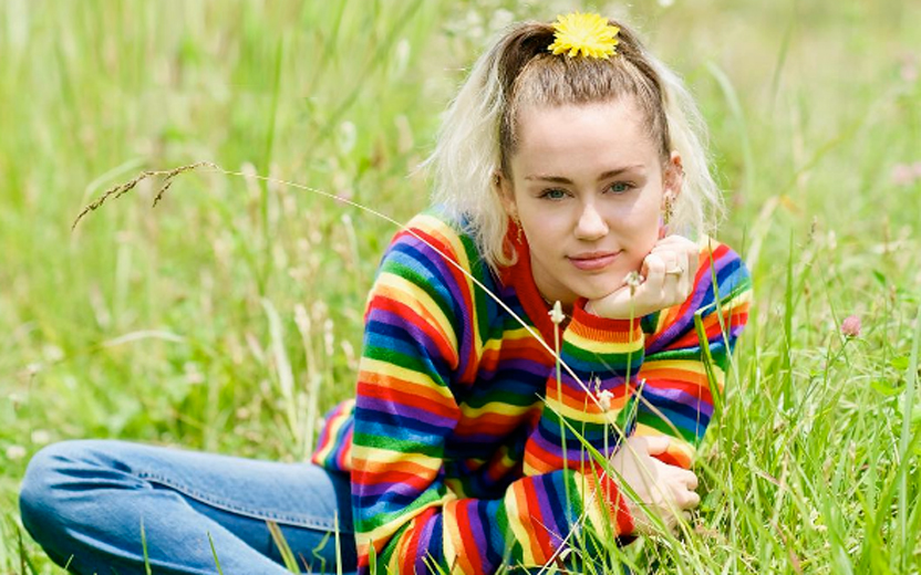 miley cyrus usando roupa colorida em meio a campo verde