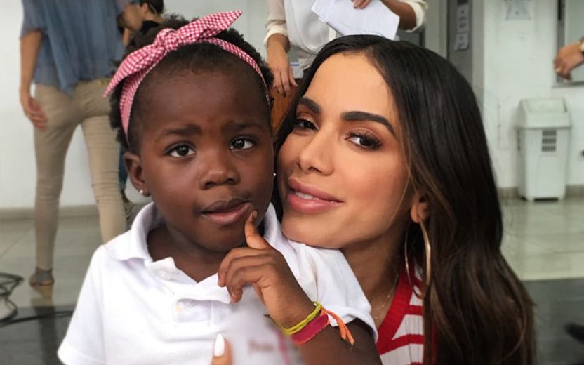 Anitta abraça Titi, filho de bruno gagliasso, que usa tiara rosa e camiseta branca