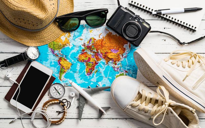 mapa, tênis, celular, óculos de sol, câmera fotográfica e outros objetos de viagem sobre fundo branco
