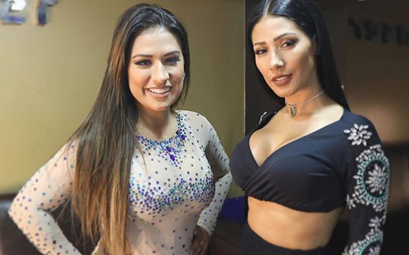 Simone e Simaria usando roupas de show e sorrindo em camarim