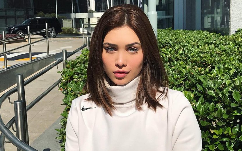 Flavia Pavanelli em jardim usando blusa de gola branca