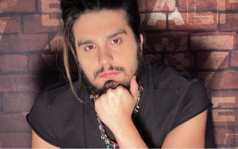 Luan Santana sentado com a mão no rosto para entrevista do Luan Santana