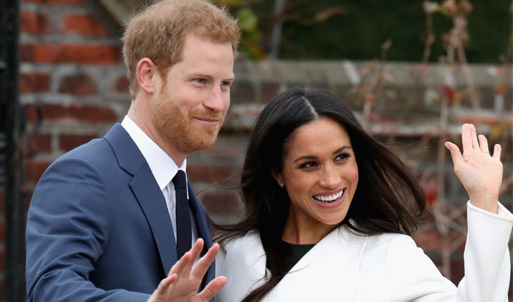 Príncipe Harry e Meghan Markle acenam paa foto