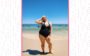 Luiza Junqueira na praia usando maiô preto