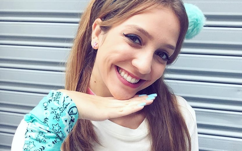Denise TMJ com mão no rosto e sorrindo